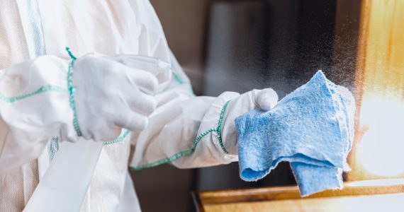 Coronavirus Pandemic. A disinfector in a protective suit and mask sprays disinfectants in house or office. Protection against COVID-19 disease. Prevention of spreding pneumonia virus with surfaces.